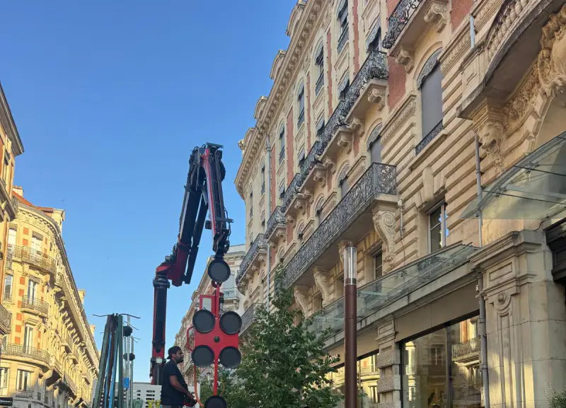 Le bras de la grue déployé au-dessus de la rue, entre les façades du centre de Toulouse