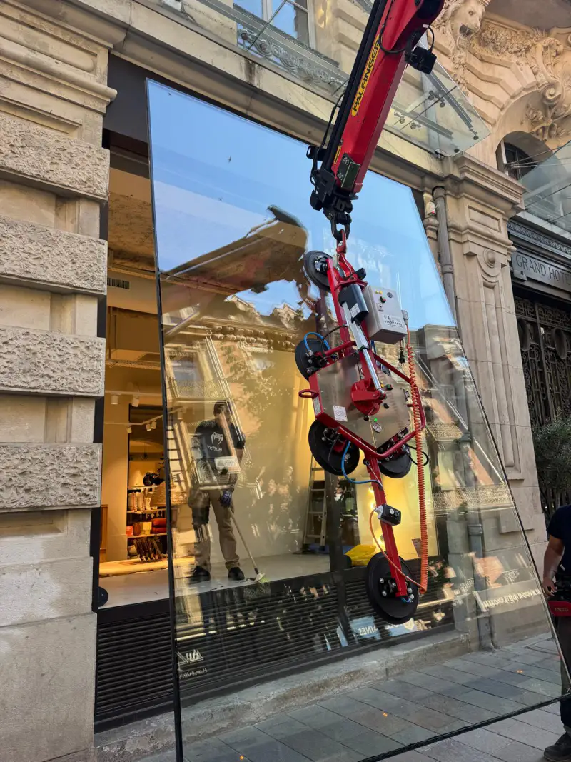 Vitrine de plus de 450 kg suspendue au palonnier à ventouses devant l'ouverture du commerce, à Toulouse