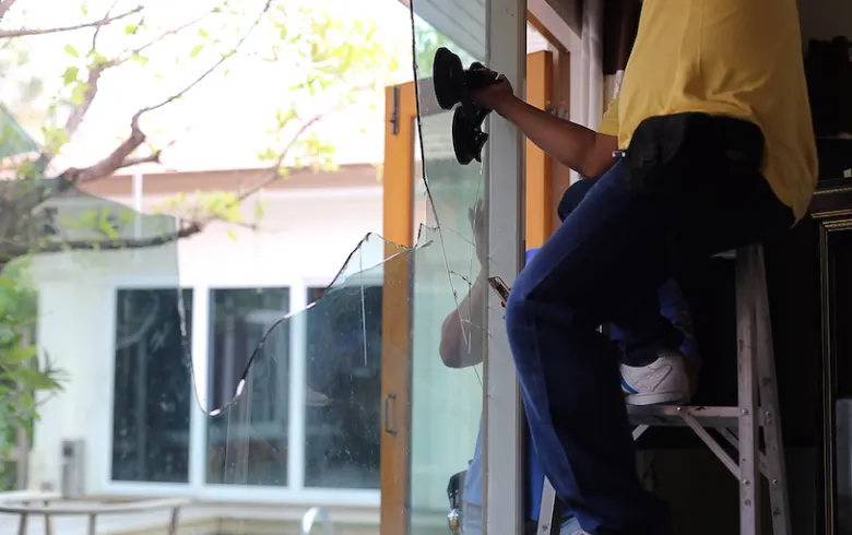 Vitrier déposant à la ventouse un panneau de verre cassé sur une baie vitrée